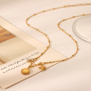 Golden stainless steel necklace with starfish, shell, and zircon pendants on a card