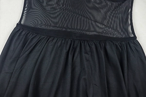Detailed view of the sheer mesh stitching and waist pleats on a black mini dress