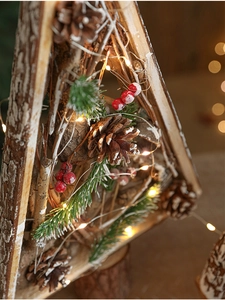 Close-up of wooden Christmas tree with pine cones, red berries and warm LED lights