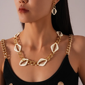 Détail du collier en chaîne dorée avec losanges en émail blanc et strass sertis avec soin