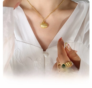 Detail of 18k gold plated titanium steel shell pendant necklace and green gemstone ring
