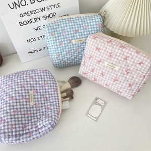Detailed close-up of quilted cotton cosmetic bags with bow patterns and zipper closure