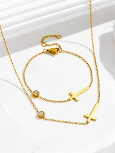 Detailed view of gold cross necklace and bracelet set with sparkling zircon stones