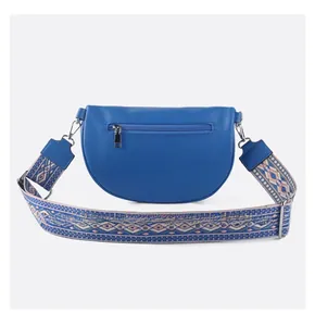 Detail view of royal blue crescent bag with litchi grain texture and ethnic woven strap