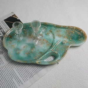 Detail of green marble resin tray with gold foil flakes and wavy edges with handle