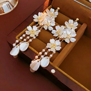 Elegant long fringe floral earrings with pearls and gold accents on yellow velvet base