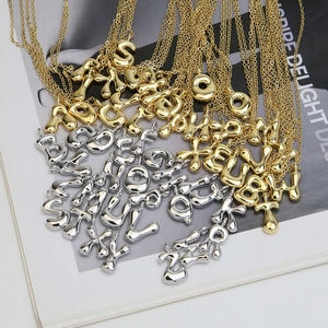 3D puffy alphabet pendant necklace set in gold and silver finish on a magazine background