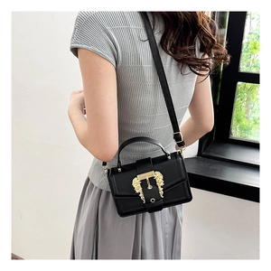 Detail of black leather crossbody bag with a vintage gold lion head buckle embellishment