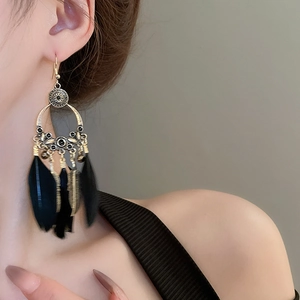 Détail de longues boucles d'oreilles bohèmes à plumes noires avec finition bronze antique