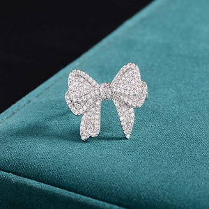 Sparkling bow-shaped silver ring with white zircons on a dark green velvet jewelry box
