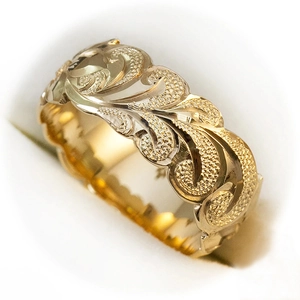 Macro detail of a wide gold ring featuring intricate wave floral engravings and matte textures