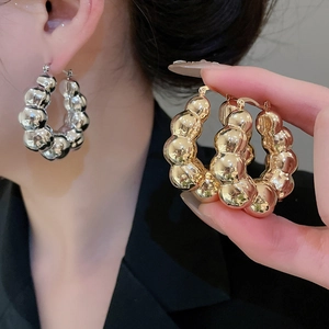 Detailed view of large C-shaped bubble texture hoop earrings in gold and silver finish