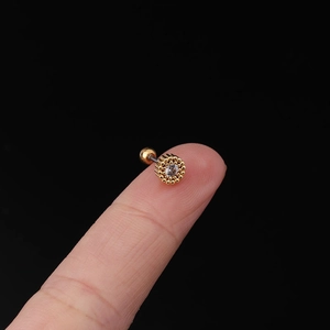 Macro view of a 20G gold zircon cartilage stud on a fingertip for size reference