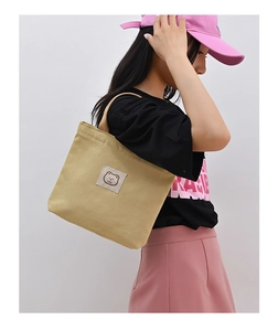 Detail of khaki canvas tote bag featuring bear embroidery and LOVE text in a lifestyle setting