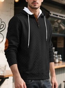 Détail d'un sweat à capuche noir matelassé avec patchs aux coudes et col à boutons
