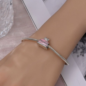 Close-up of pink enamel holiday suitcase charm on a silver snake chain bracelet