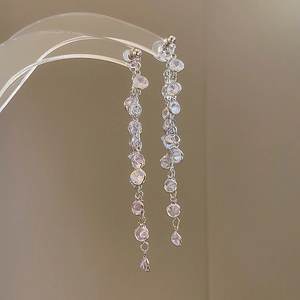Detailed close-up of long tassel earrings with sparkling zircon stones on a silver base