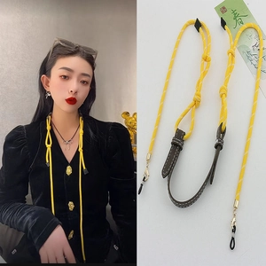 Detailed view of yellow woven glasses strap with leather joiner and rubber loops