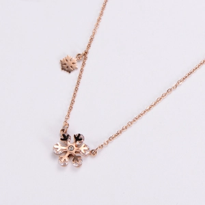 Rose gold stainless steel snowflake necklace with cubic zirconia on light background