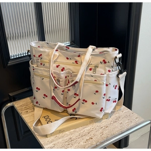Detail of white cherry print canvas tote bag with functional exterior zipper pockets