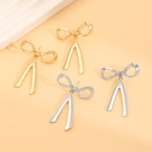 Detailed view of elegant gold and silver bow earrings with hanging ribbon metallic texture