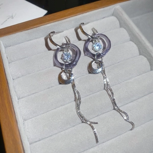 Détail macro de boucles d'oreilles à pompon argenté avec anneau acrylique violet