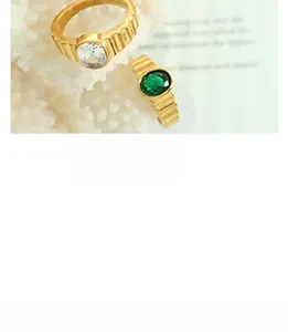 Detail of vintage gold rings with vertical texture featuring emerald and zircon stones