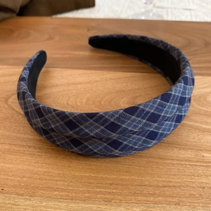 Detailed close-up of dark blue plaid fabric headband with non-slip lining on wood surface