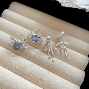 Detailed shot of silver bow pearl earrings with blue zircon in a jewelry box