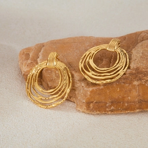 Irregular gold multilayer circular stud earrings placed on natural stone background