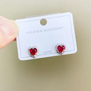 Detailed macro of a heart-shaped ruby stud earring with 925 silver pin and diamond halo