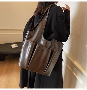 Detail of a large dark brown PU leather tote bag with functional double front pockets