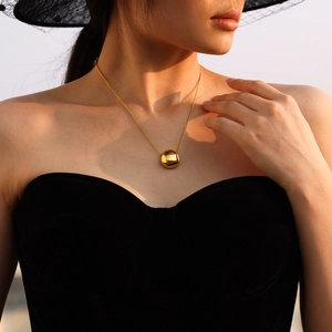 Minimalist 18K gold plated round sphere pendant necklace shown on a model outdoors