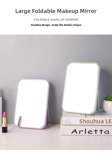 Detail view of foldable purple and green makeup mirrors with adjustable brackets on a desk