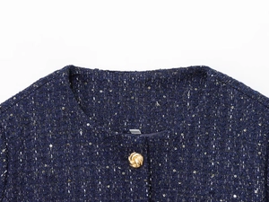 Dettaglio giacca in tweed blu navy con paillettes e bottone dorato a spirale in primo piano