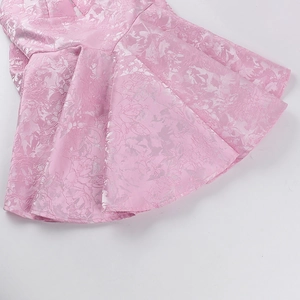Detail view of pink jacquard fabric showing floral textures on the dress hem
