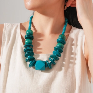 Detail of teal wooden beads and a geometric cube pendant on a boho style necklace