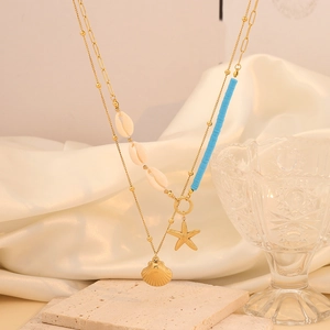 Macro detail of bohemian layered gold necklace with shell and starfish pendants