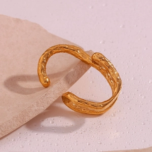 Macro shot of 18K gold plated cuff bracelet with irregular lava texture on natural stone