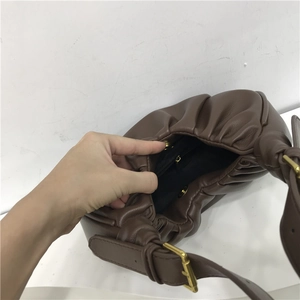 Detailed interior of dark brown pleated cloud bag showing magnetic clasp and zipper pocket