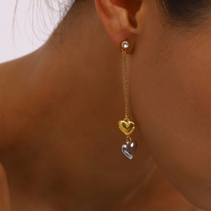 Elegant gold chain tassel earrings with two-tone heart pendants and zircon studs on a model