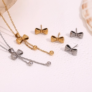 Macro shot of elegant gold and silver bow pendant necklace and matching stud earrings set