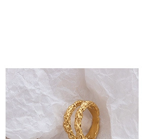 Vue macro d'une bague dorée double épaisseur avec texture martelée sur papier froissé