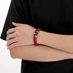 Detail of red double-layered braided leather bracelet with gold beads on male wrist