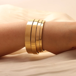 Macro detail of four gold titanium steel bracelets in varying widths with mirror finish