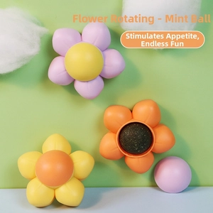 Rotating flower catnip ball toy in purple and yellow on a green and blue background