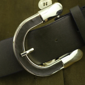 Elegant lapel dress belt detail with a polished silver U-shaped buckle and dark leather