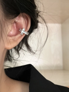 Close-up of silver cross ear cuff with sparkling zircons worn on the ear bone