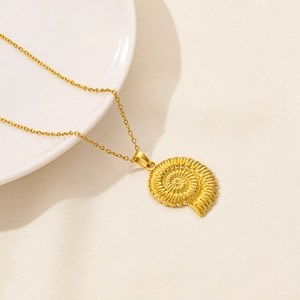 Detailed view of a golden spiral shell pendant on a fine chain over a textured background