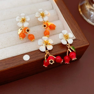 Detailed close-up of vintage flower and berry drop earrings on beige velvet display